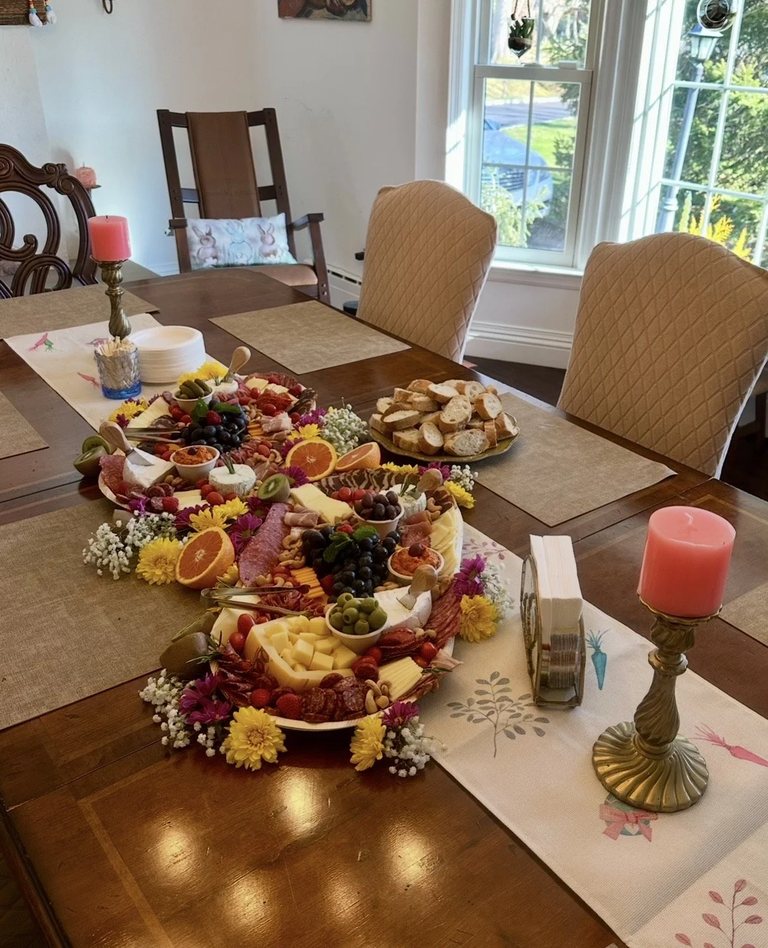 Charcuterie board with cured meats, cheese, olives and edible flowers next to sliced baguette