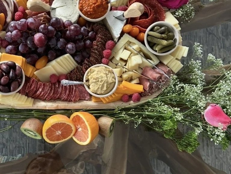 Close detail of hummus, cornichons and sliced cheese on a MEZA board