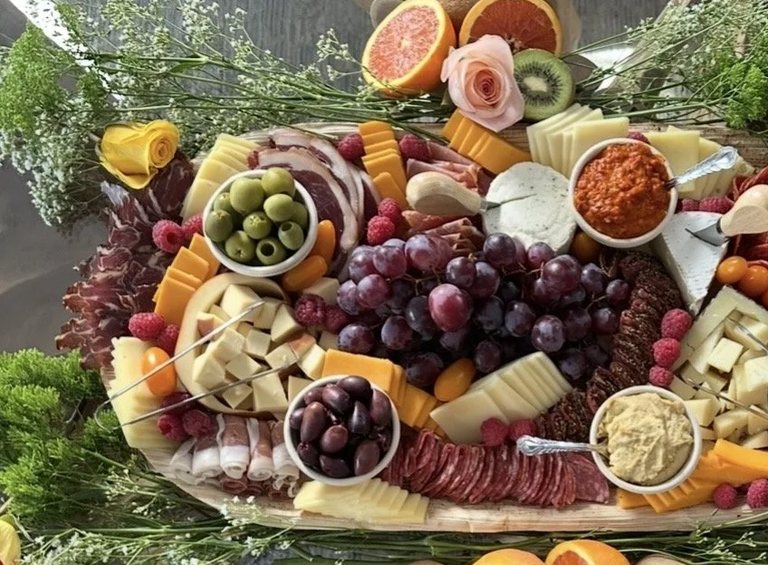 Close detail of green olives, cheddar wedges and prosciutto on a MEZA grazing board