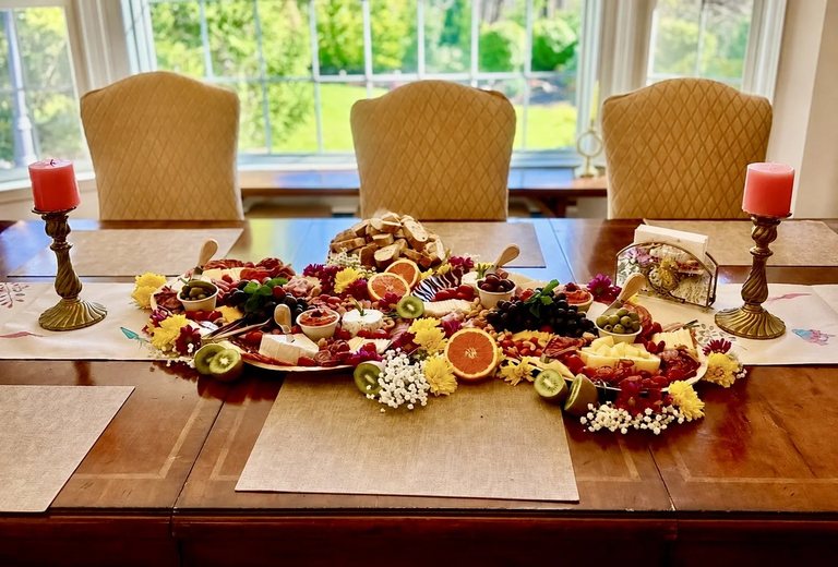 A full grazing table of charcuterie, cheese and fresh fruit styled down a dining table with candles
