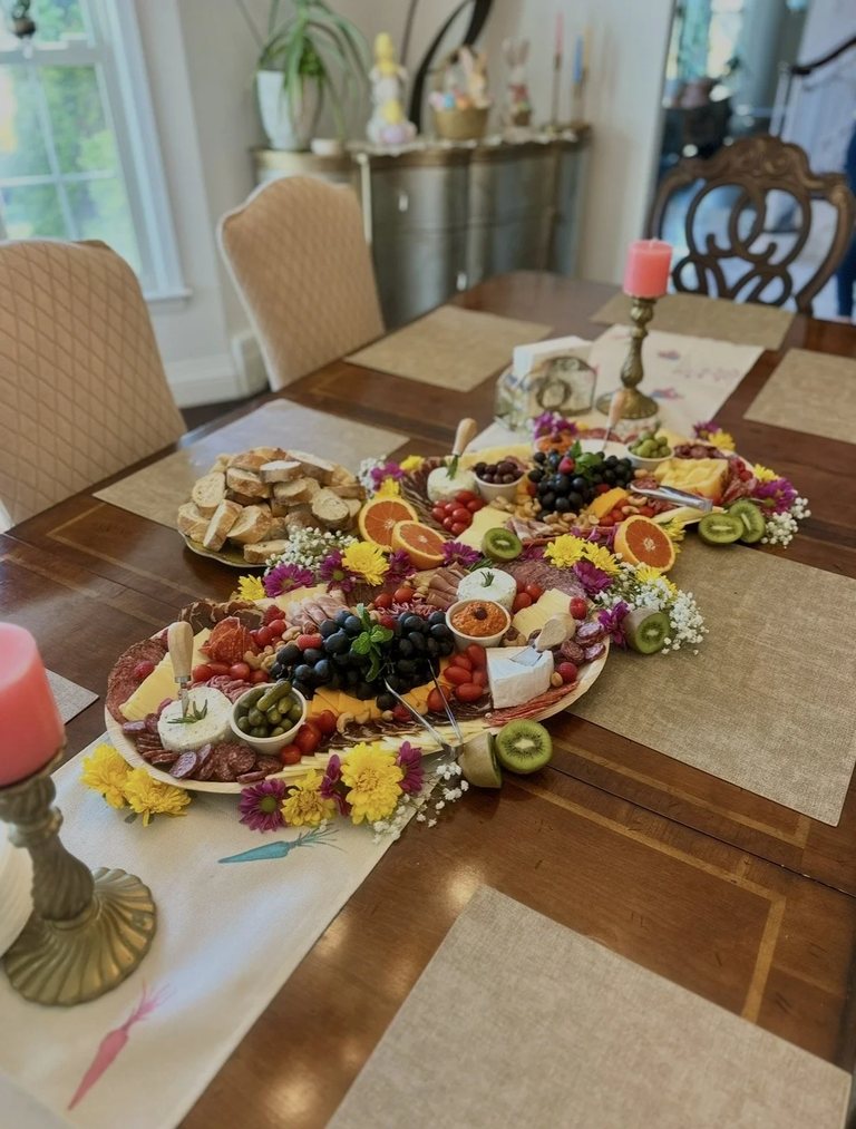 Charcuterie boards set on a dining table in a bright home with candlesticks and place settings